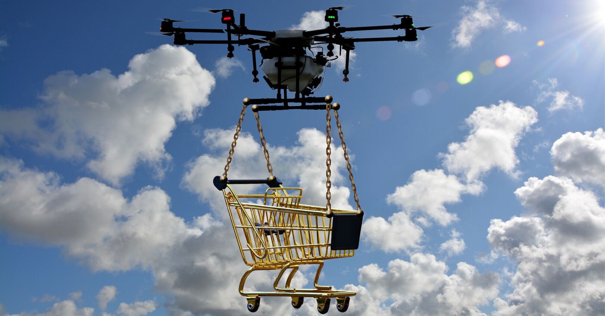 A drone flying in a blue sky with fluffy white clouds, carrying a miniature gold shopping cart suspended by chains 