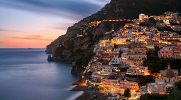 City buildings on mountain near body of water during eveningtime