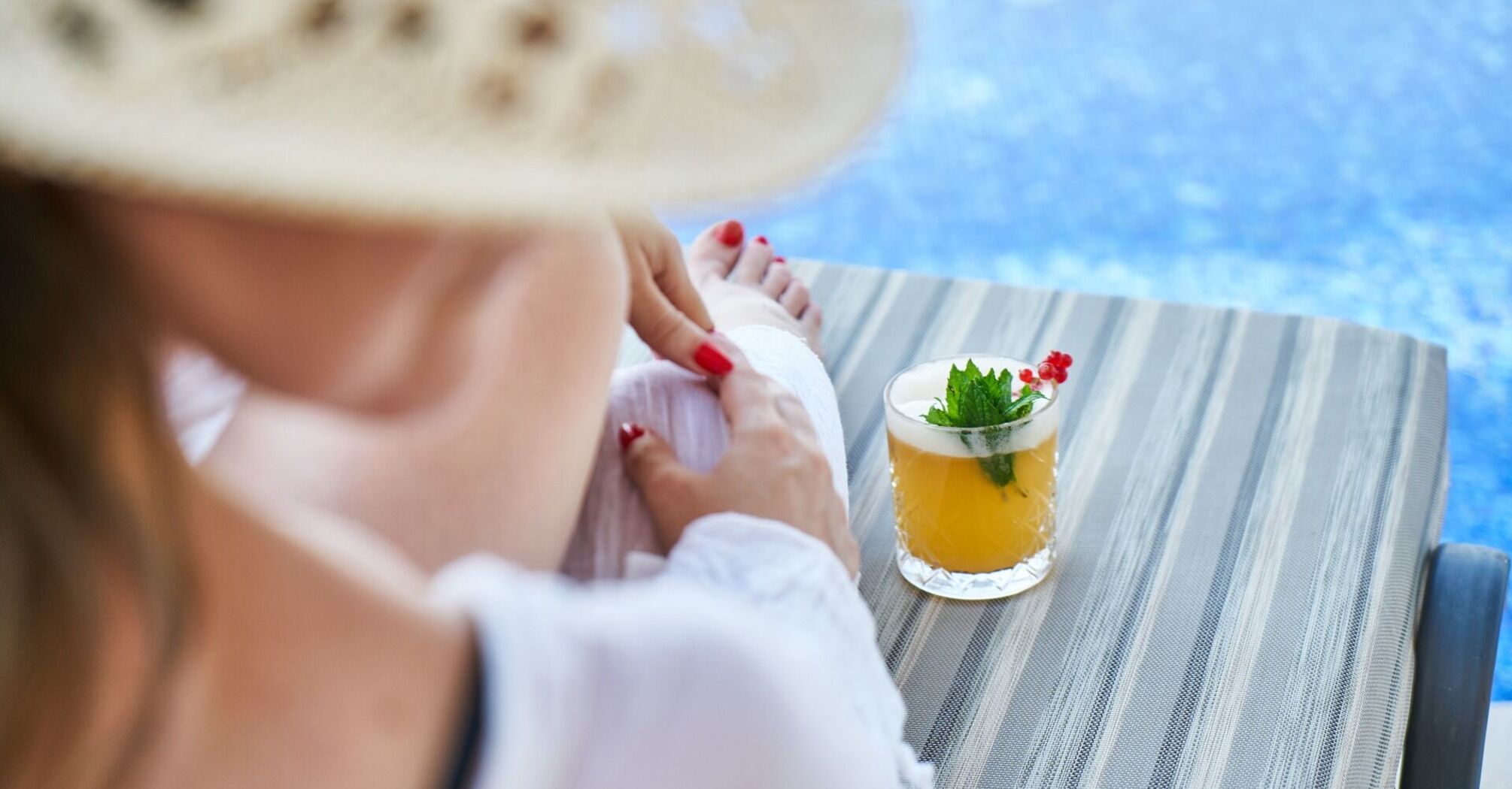 A woman relaxing by a poolside with a tropical cocktail on the table