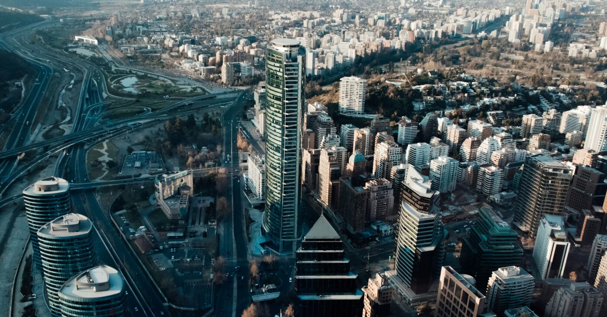 Aerial view of Santiago, Chile, showcasing the city's dense architecture with modern skyscrapers, residential buildings, and busy roadways 