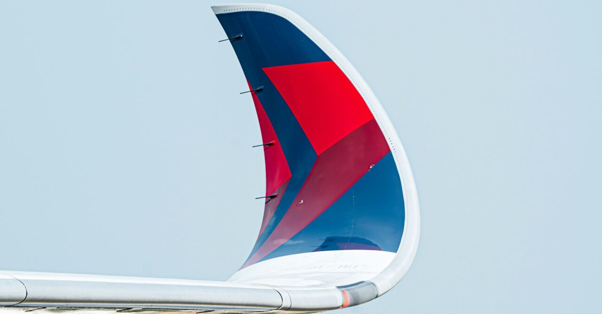 The wing end of an airplane that is flying in the sky