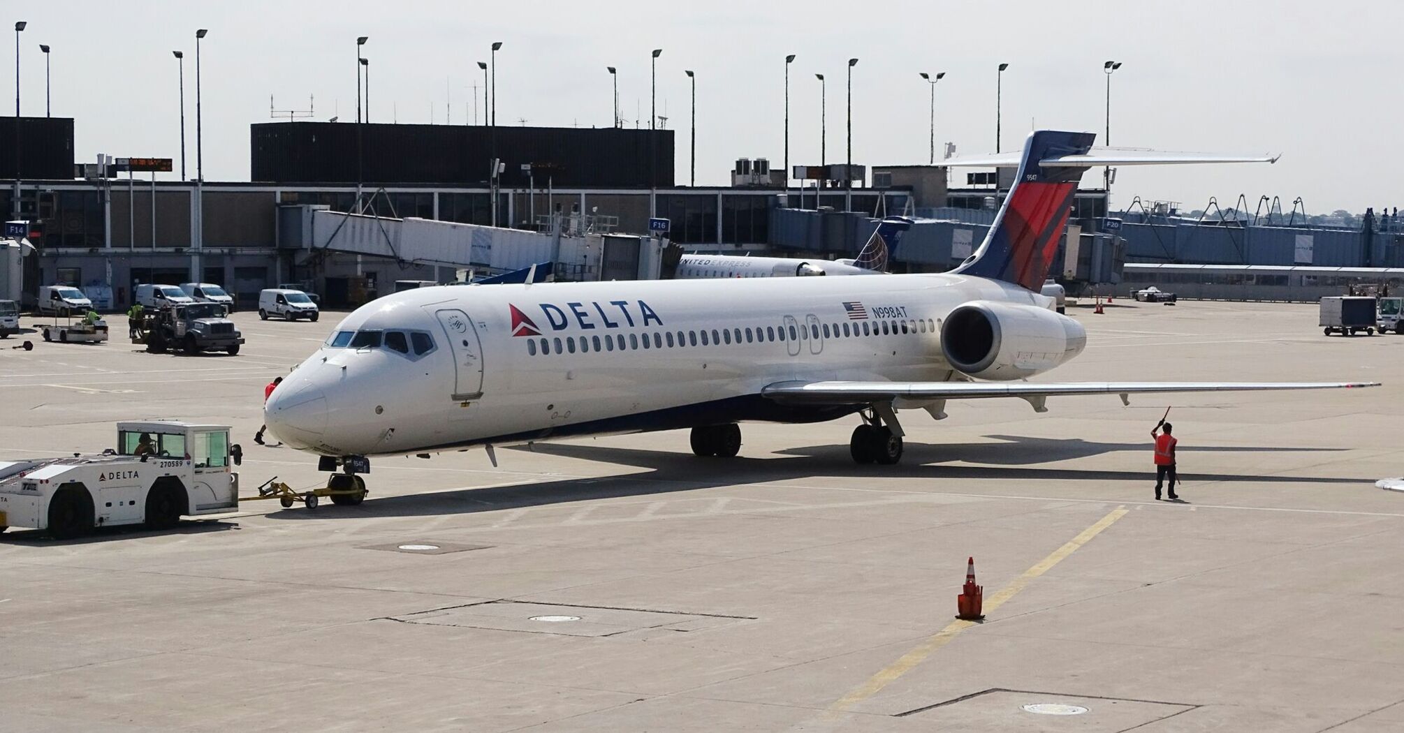 A Delta Airlines aircraft on the tarmac with airport facilities in the background