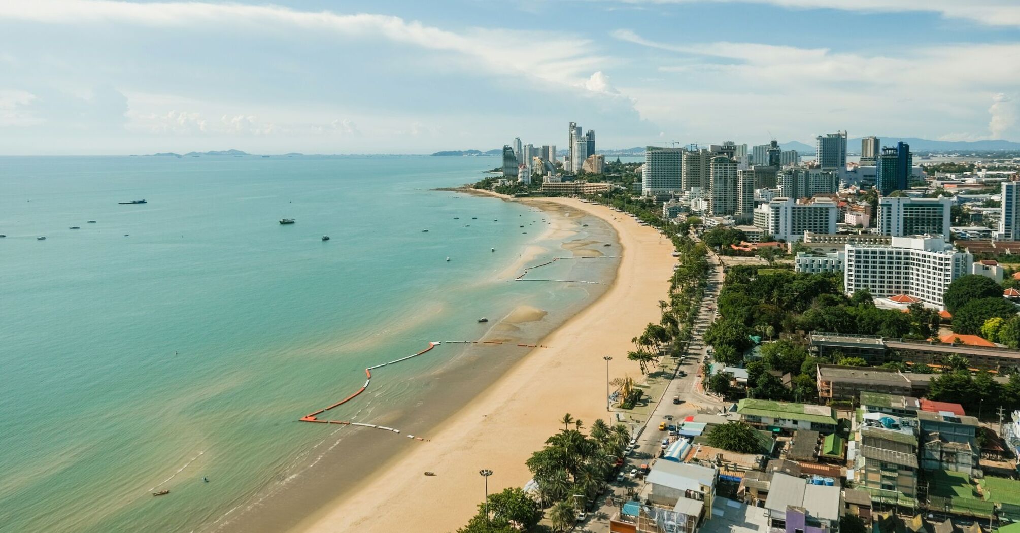 A panoramic view of Pattaya, Thailand, showcasing the expansive sandy beach along the coast with boats in the water