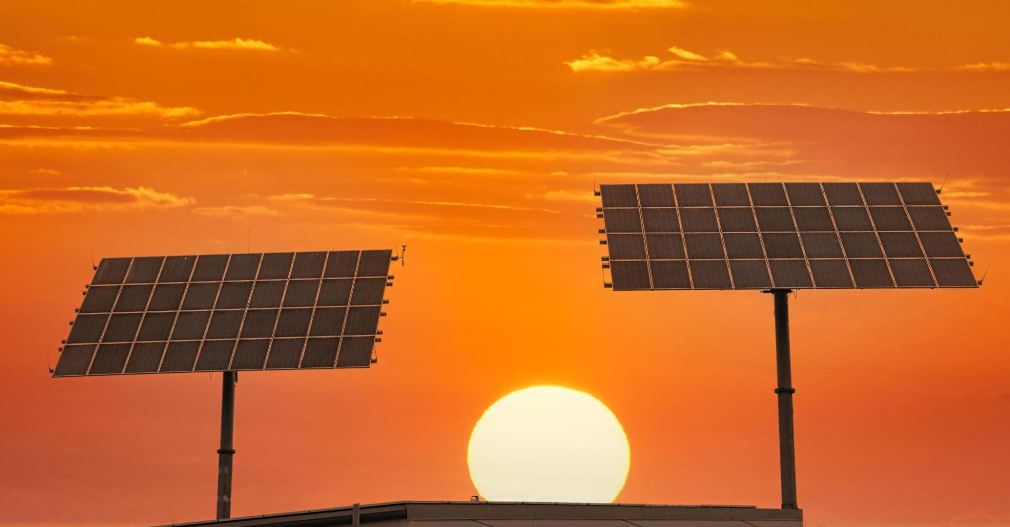Two solar panels against sunset background