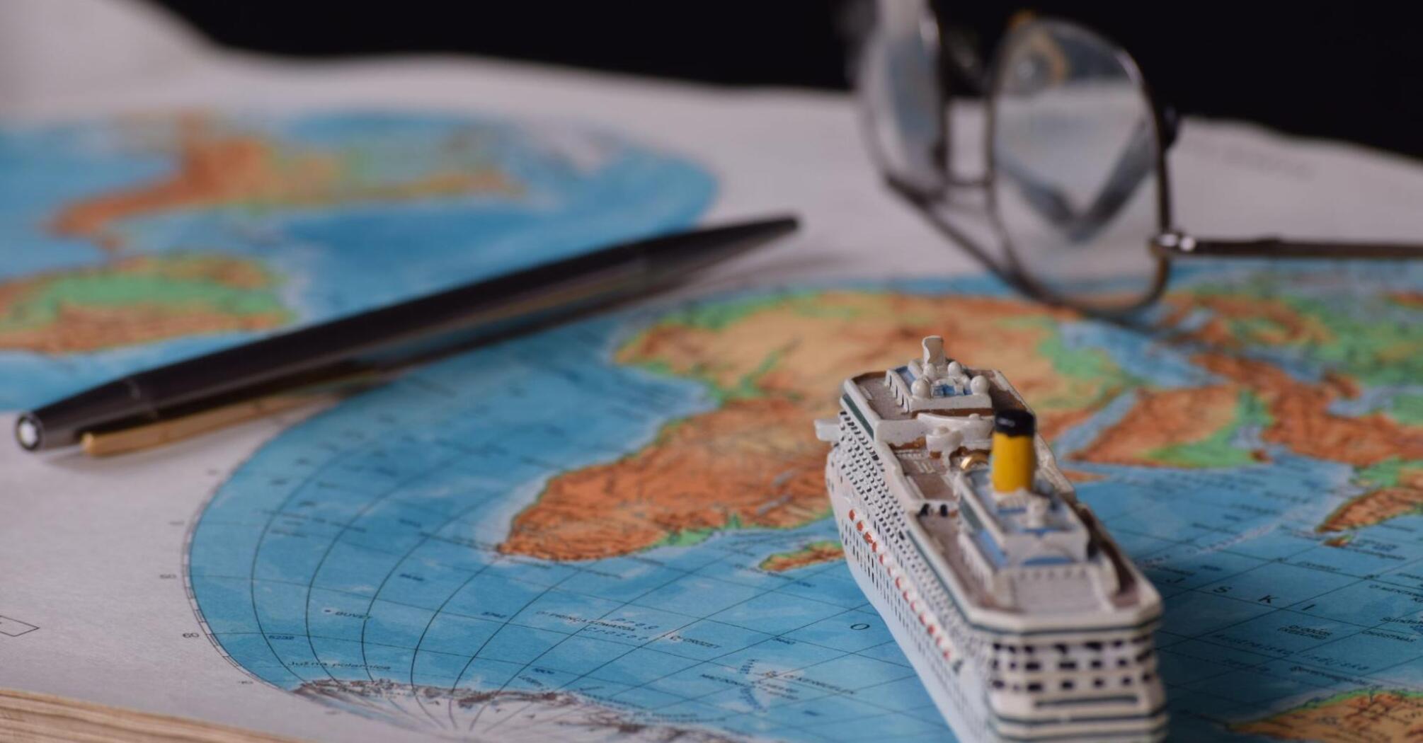 Small toy boat on the background of a world map