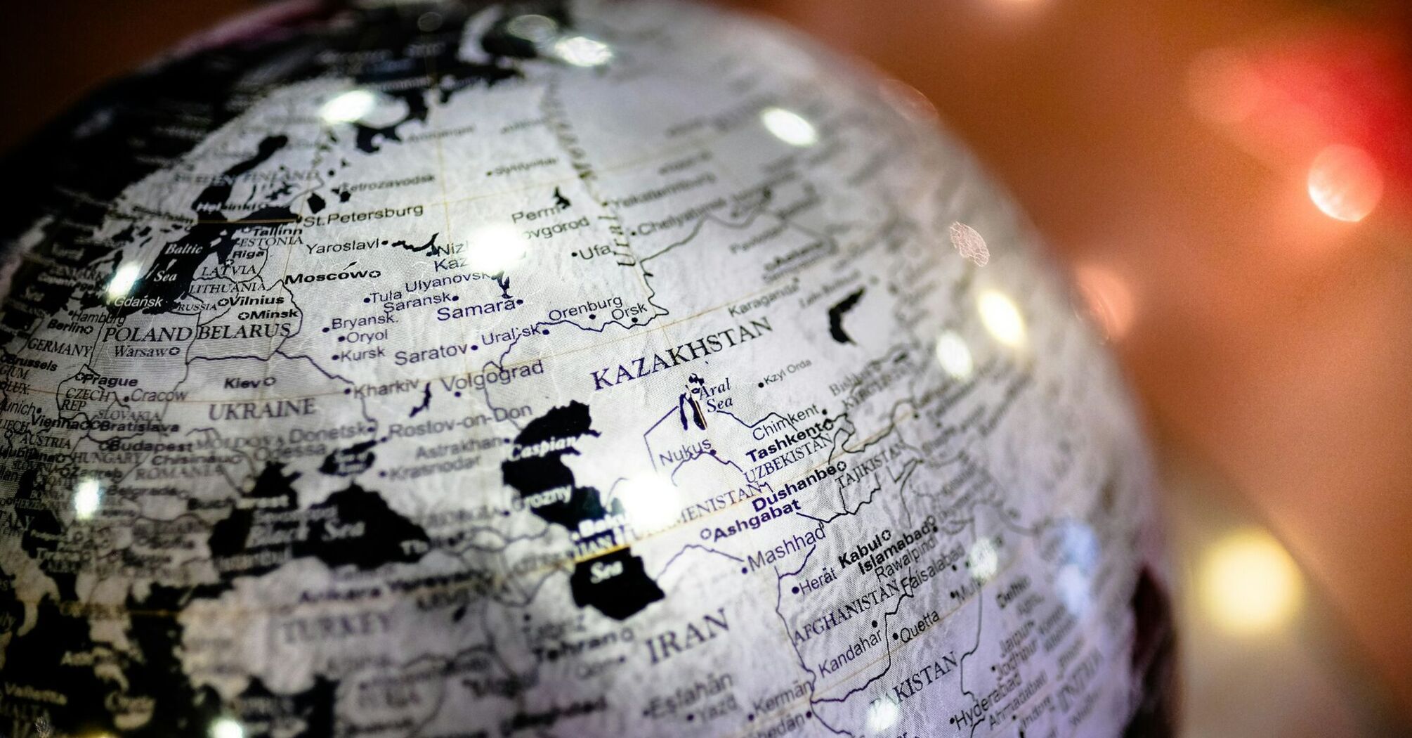 A detailed globe highlighting the country of Kazakhstan, with surrounding countries and major cities labeled, under soft lighting