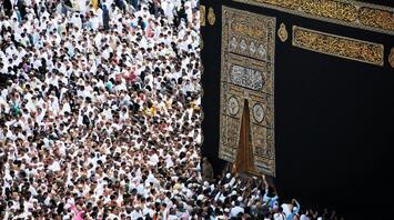A large crowd of people dressed in white Ihram clothing performing the Islamic pilgrimage, Hajj, around the Kaaba in Mecca