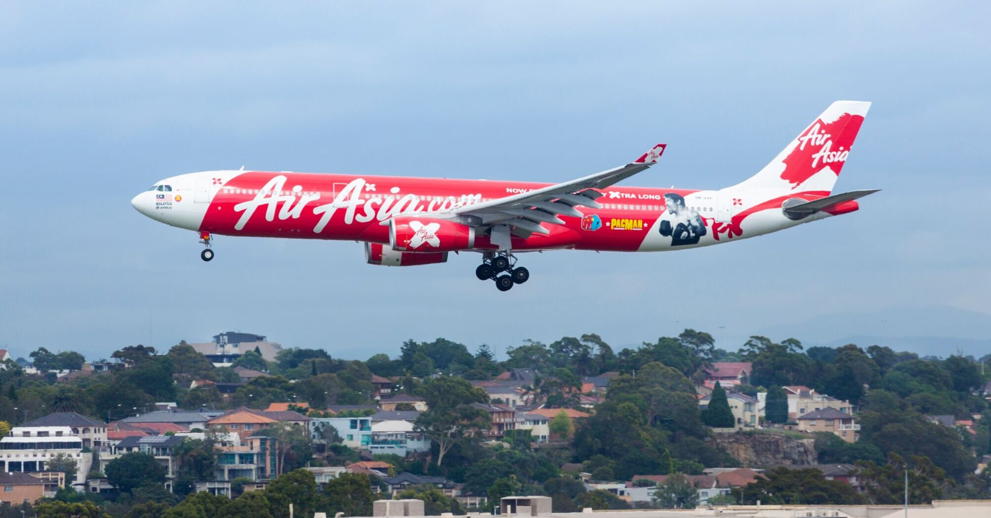 White and red air asia passenger plane above ikea building during daytime