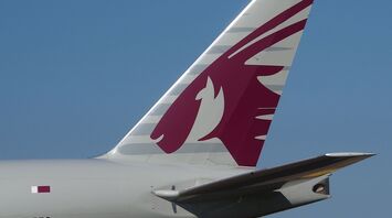 Close-up of the tail of a Qatar Airways aircraft, showcasing the airline's iconic oryx logo in maroon on a white background