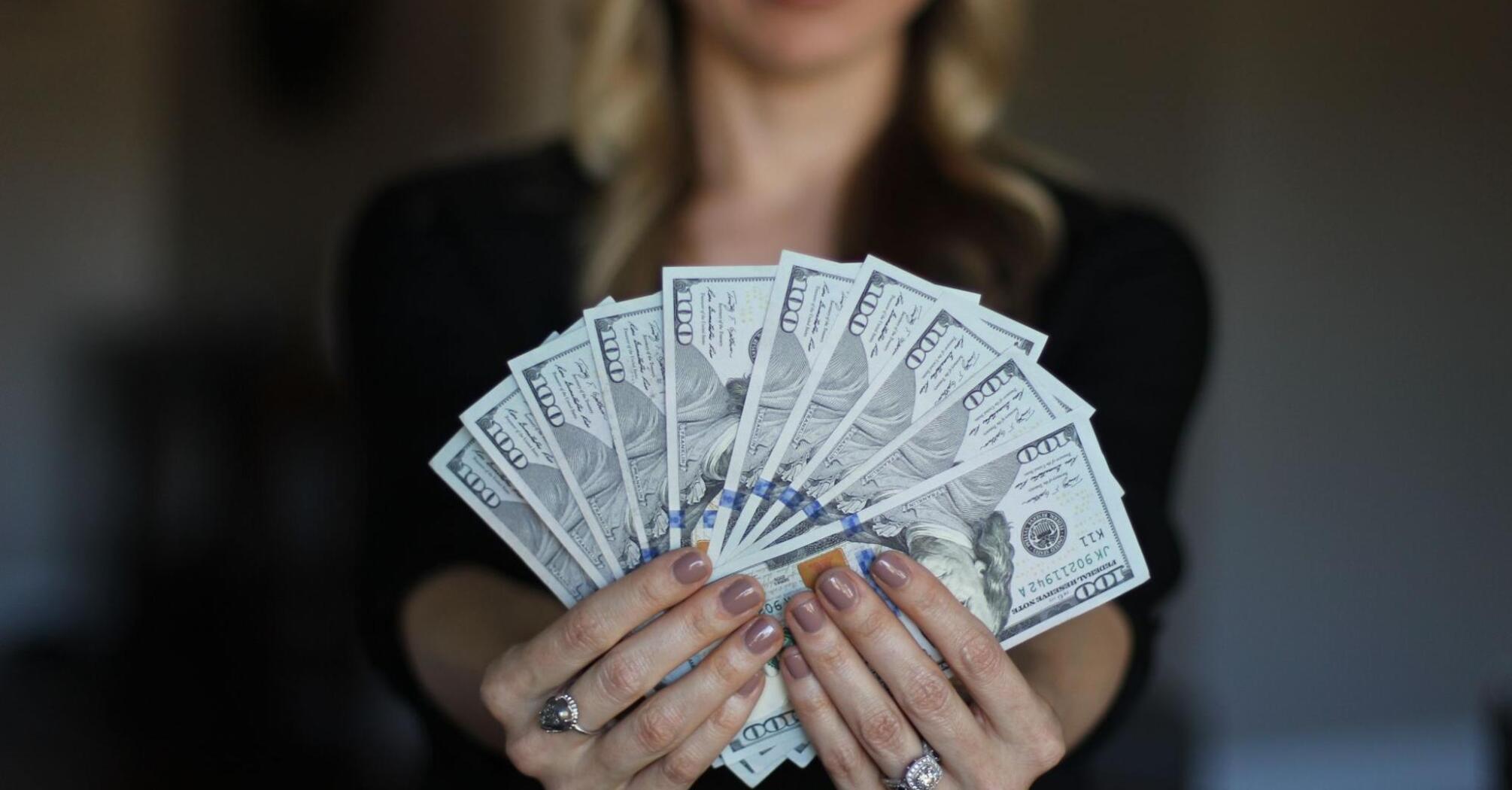 Woman holding $100 bills in her hands