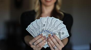 Woman holding $100 bills in her hands