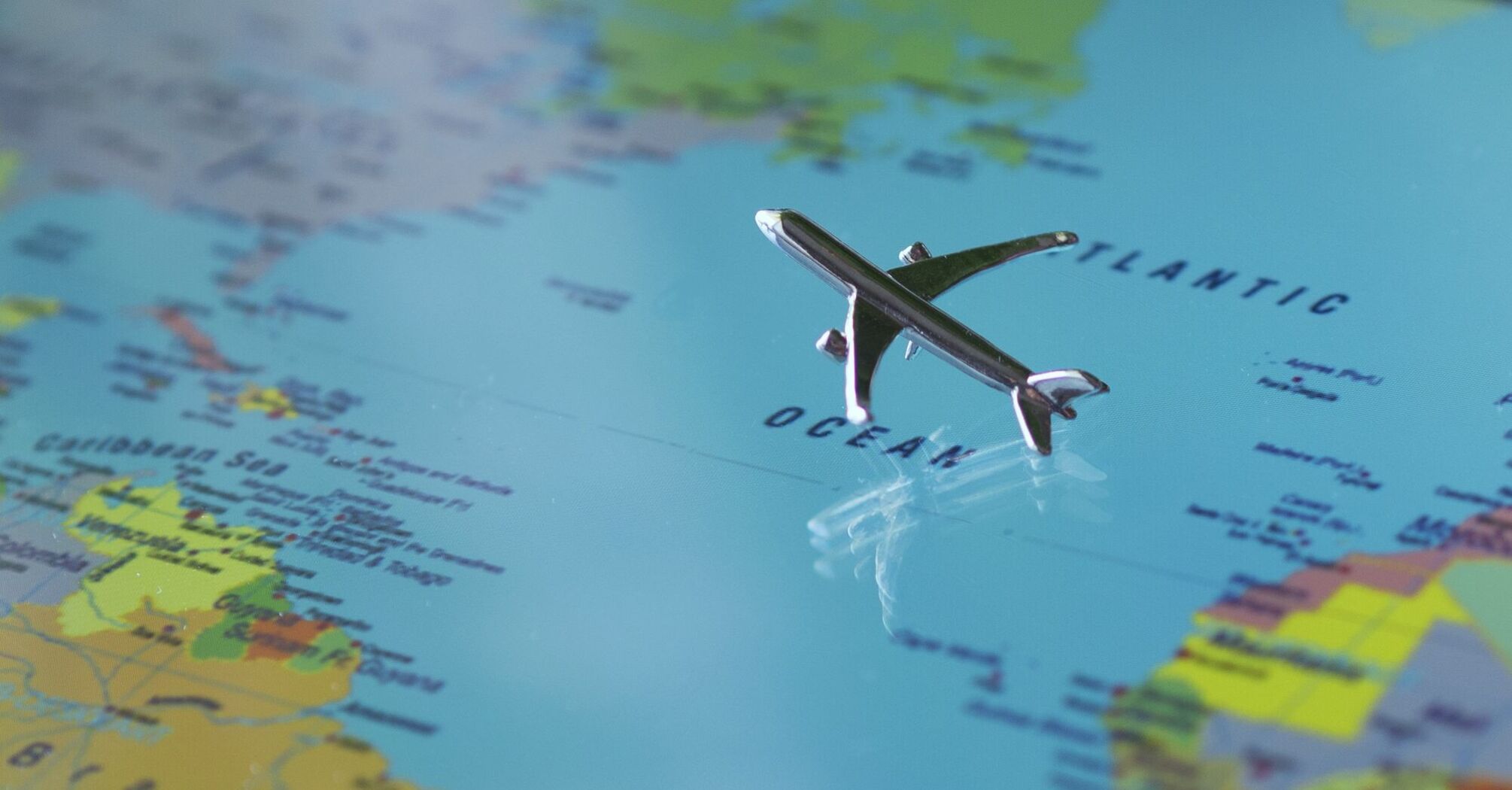 A small toy airplane positioned on a world map over the Atlantic Ocean area