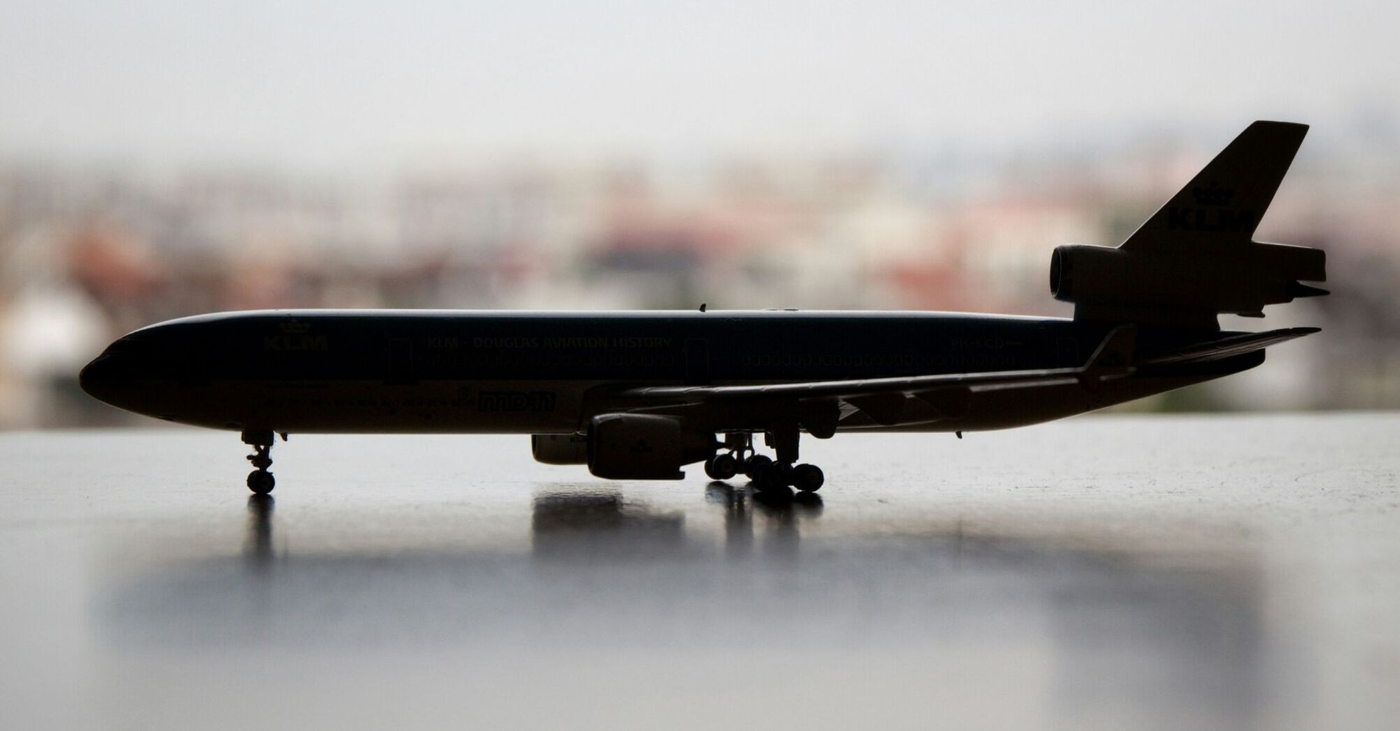 Silhouette of a model airplane against a blurred cityscape background