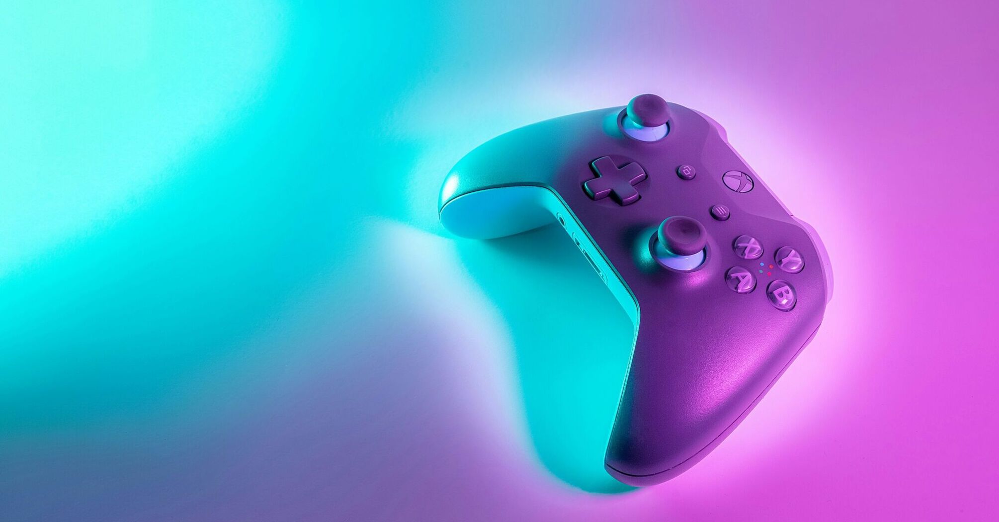 A colorful game controller with a gradient from purple to teal on a dual-tone background of the same colors