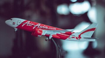 A model of an AirAsia airplane with a red and white livery on a blurred background