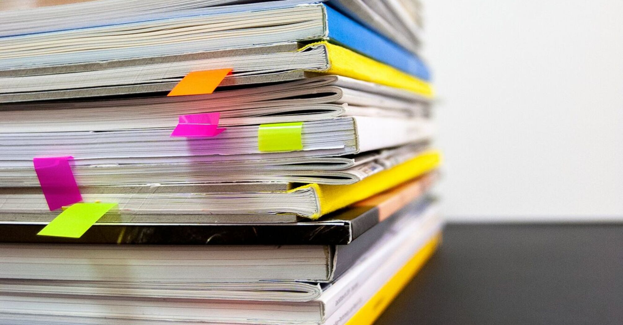 Stack of books and magazines with colorful bookmarks on a white background