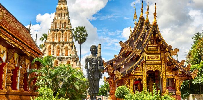 Traditional Thai temple with intricate golden decorations under blue sky