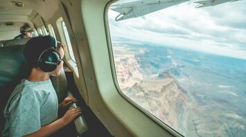 The child in the airplane cabin is looking out the window