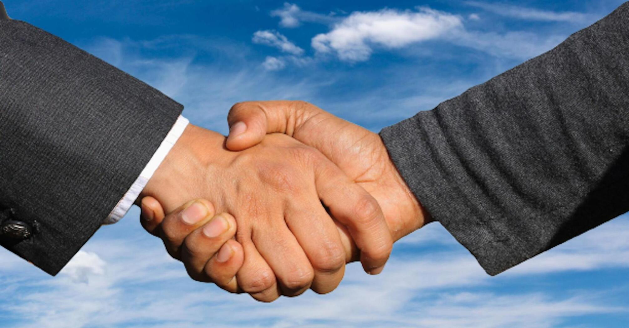 Shaking hands of two men against the sky