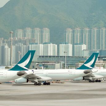 Airplanes lined up at Hong Kong airport with cityscape in the background