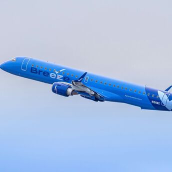 A large blue airplane flying through a blue sky