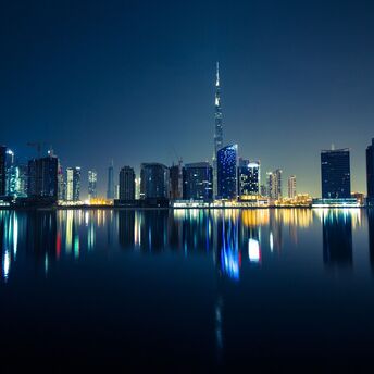 The Dubai skyline at night with reflections on water