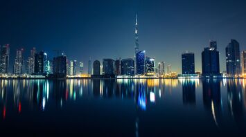 The Dubai skyline at night with reflections on water