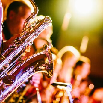 A close-up photo of saxophones being played on a brightly lit stage