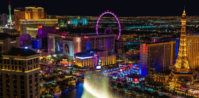 Nighttime view of the Las Vegas with illuminated hotels, the High Roller Ferris wheel, and the Bellagio fountain show