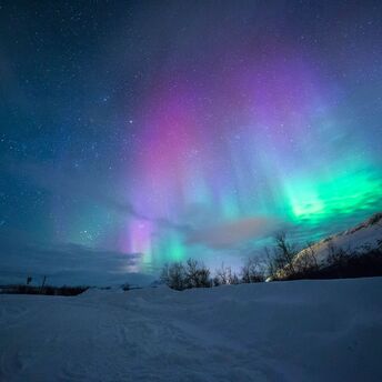 Northern lights over snow capped mountian