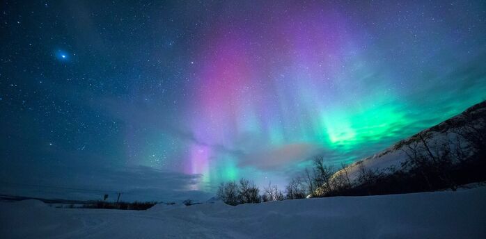 Northern lights over snow capped mountian