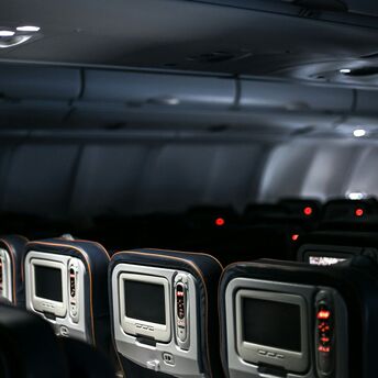 A dimly lit airplane cabin with rows of seats and personal entertainment screens