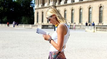 Tourist woman reading a guidebook in front of a historic building