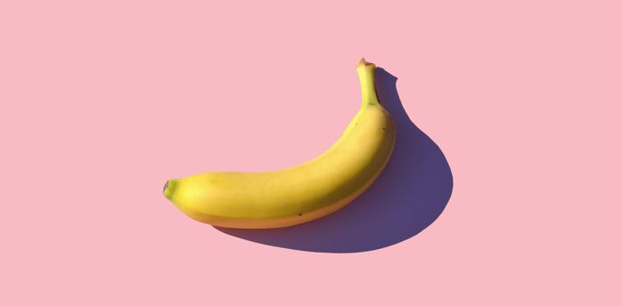 Single banana on a pink background with a shadow