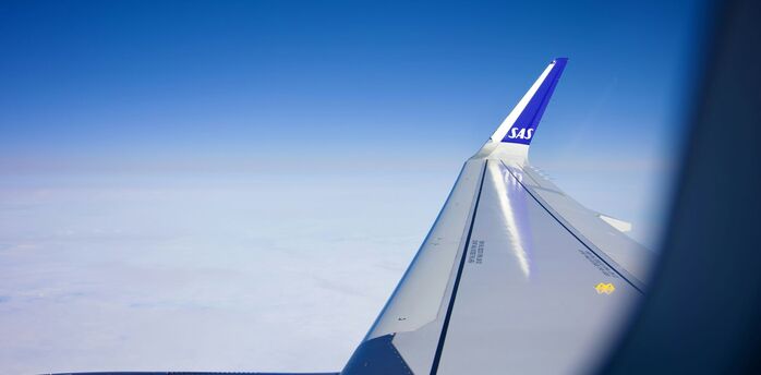 View of the sky from a plane window with the wing and SAS logo visible
