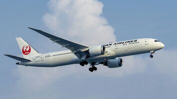 A large jetliner flying through a cloudy blue sky