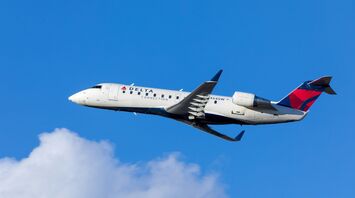 White blue and red delta airways airliner on flight under white and blue cloudy sky