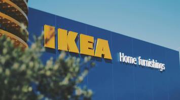 The facade of an IKEA store with the blue background and large yellow IKEA letters, the words 'Home furnishings' below, against a clear sky