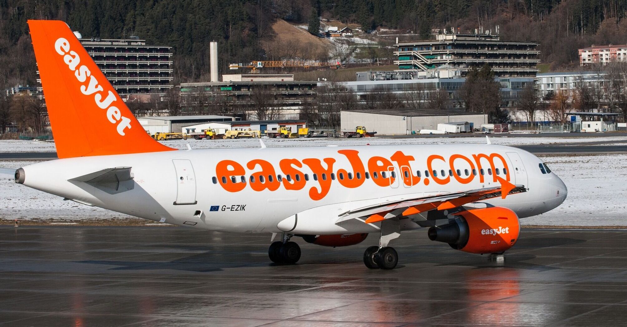 An easyJet commercial airplane on the tarmac with snowy landscape in the background 