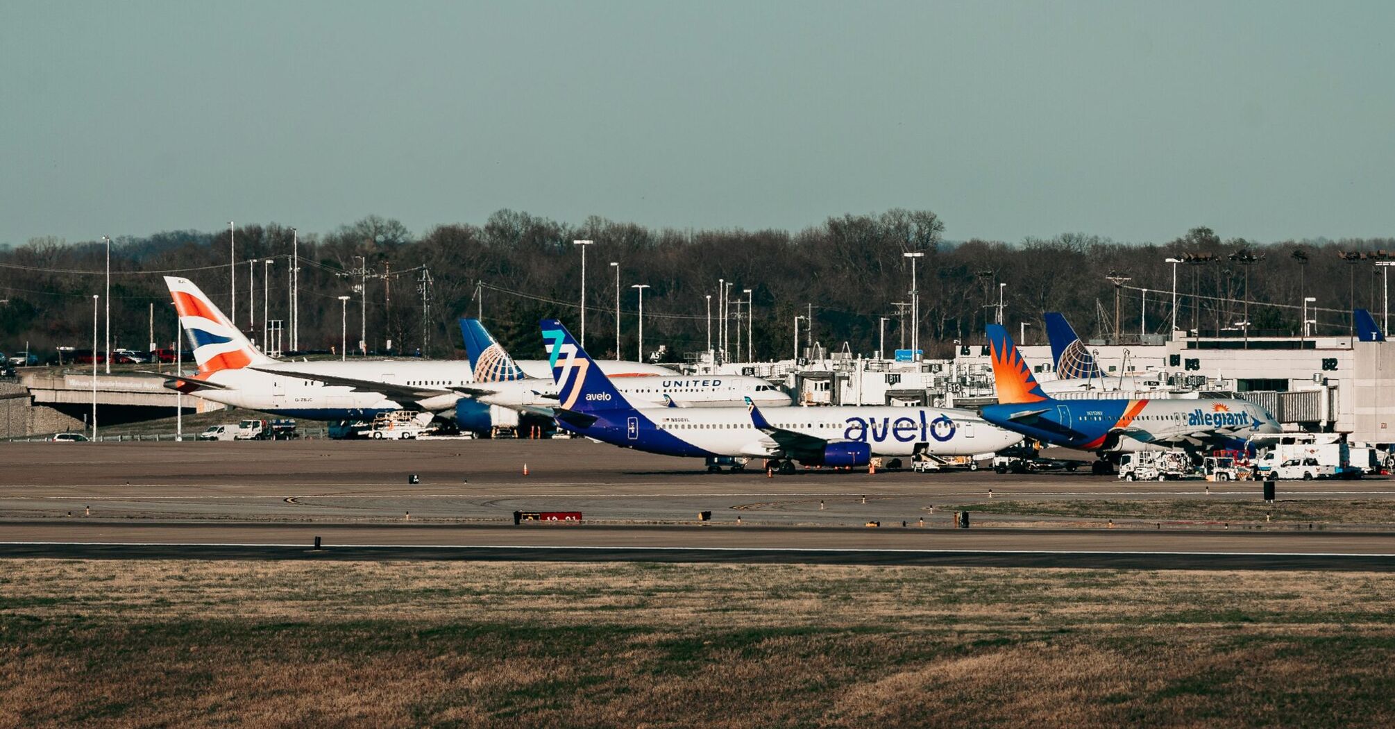 Several airplanes are parked on the runway at an airport