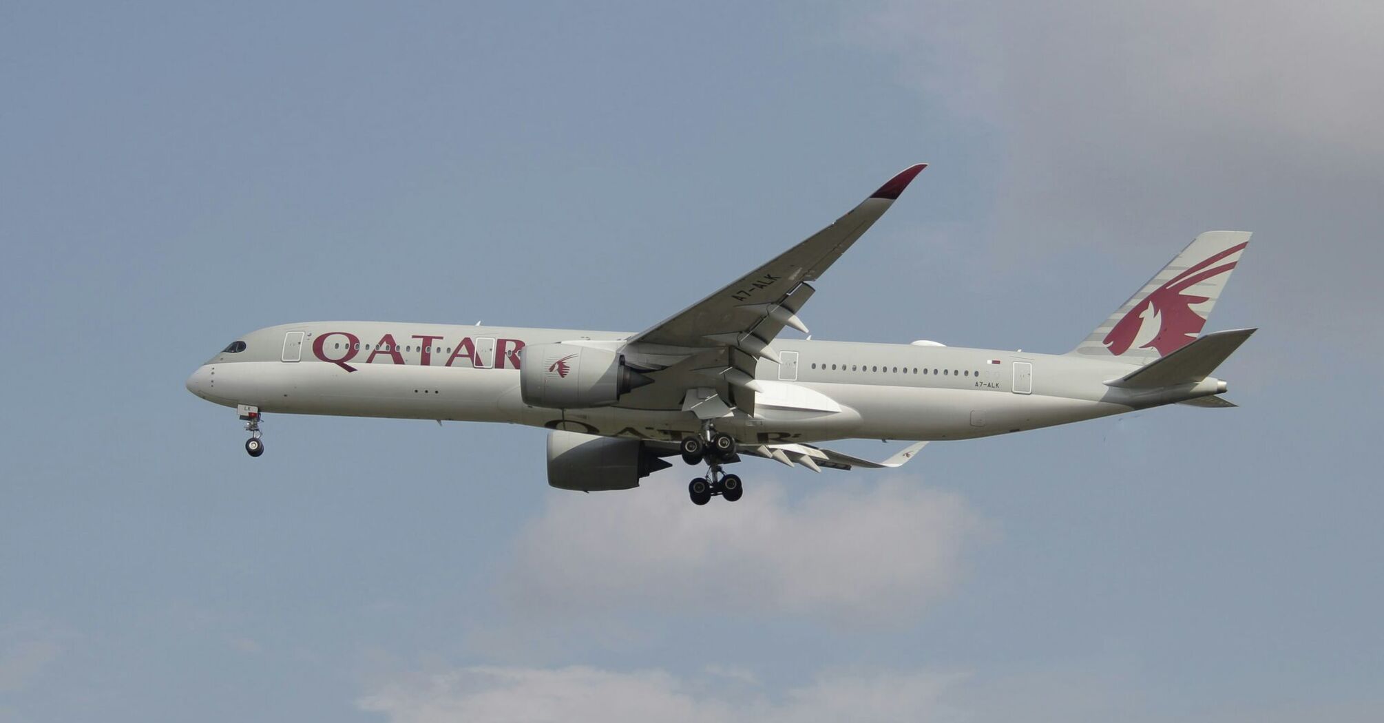 A Qatar Airways aircraft in flight against a clear sky 
