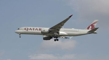A Qatar Airways aircraft in flight against a clear sky