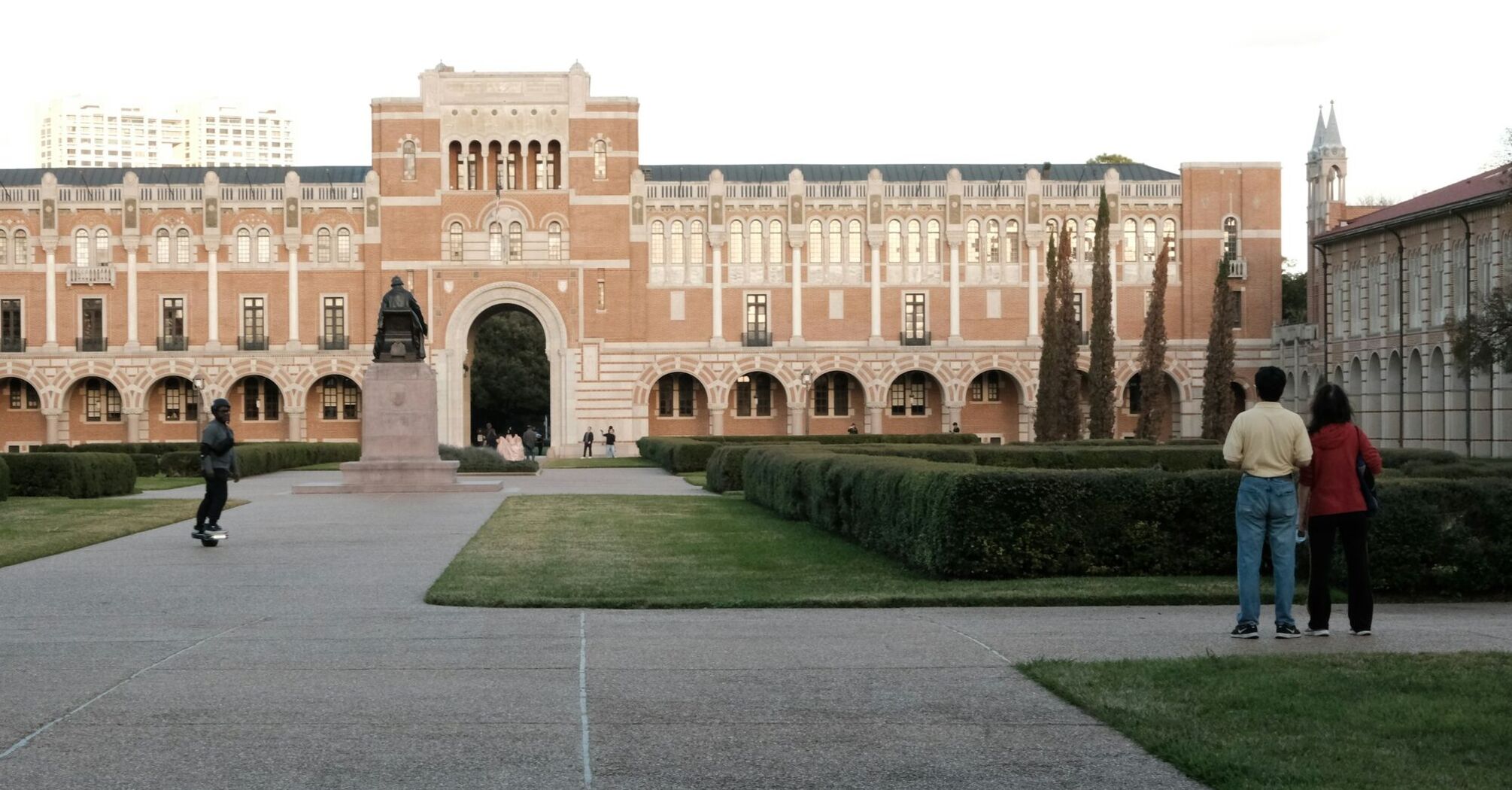 A view of Rice University's campus with people walking and a person on a skateboard