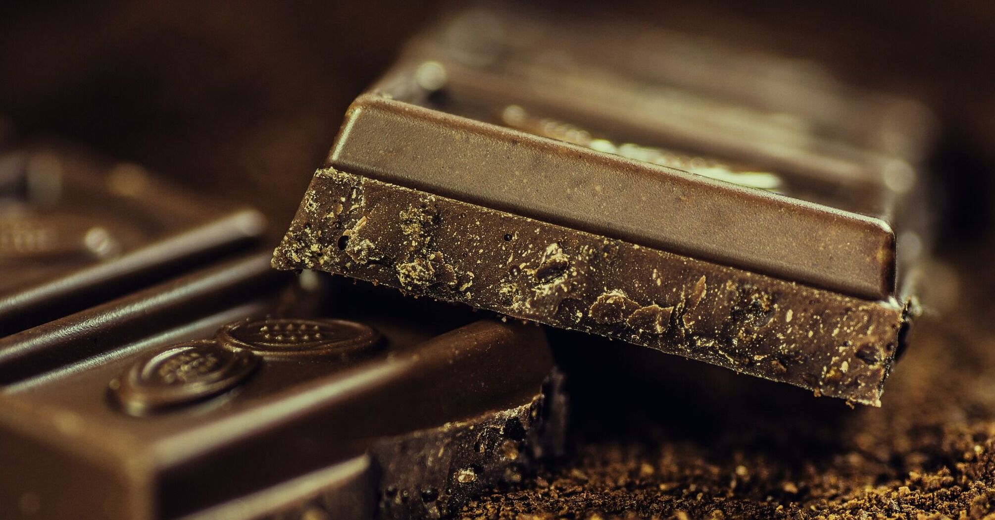 Stacked pieces of dark chocolate on a cocoa-dusted surface