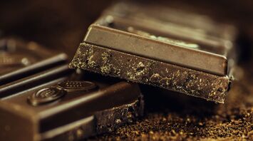 Stacked pieces of dark chocolate on a cocoa-dusted surface