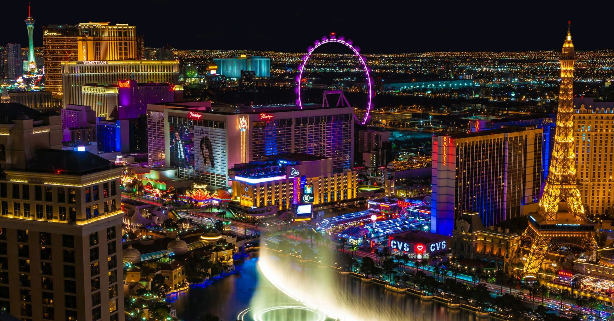 Night view of the Las Vegas Strip with illuminated landmarks and fountain show