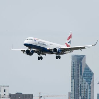 White red and blue airplane above buildings