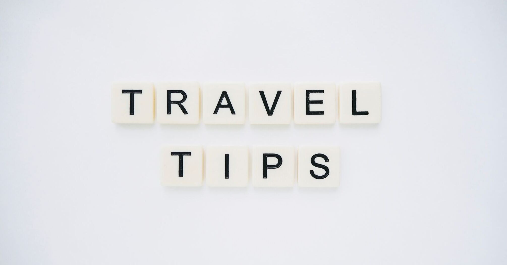 Scrabble tiles spelling out 'TRAVEL TIPS' on a white background