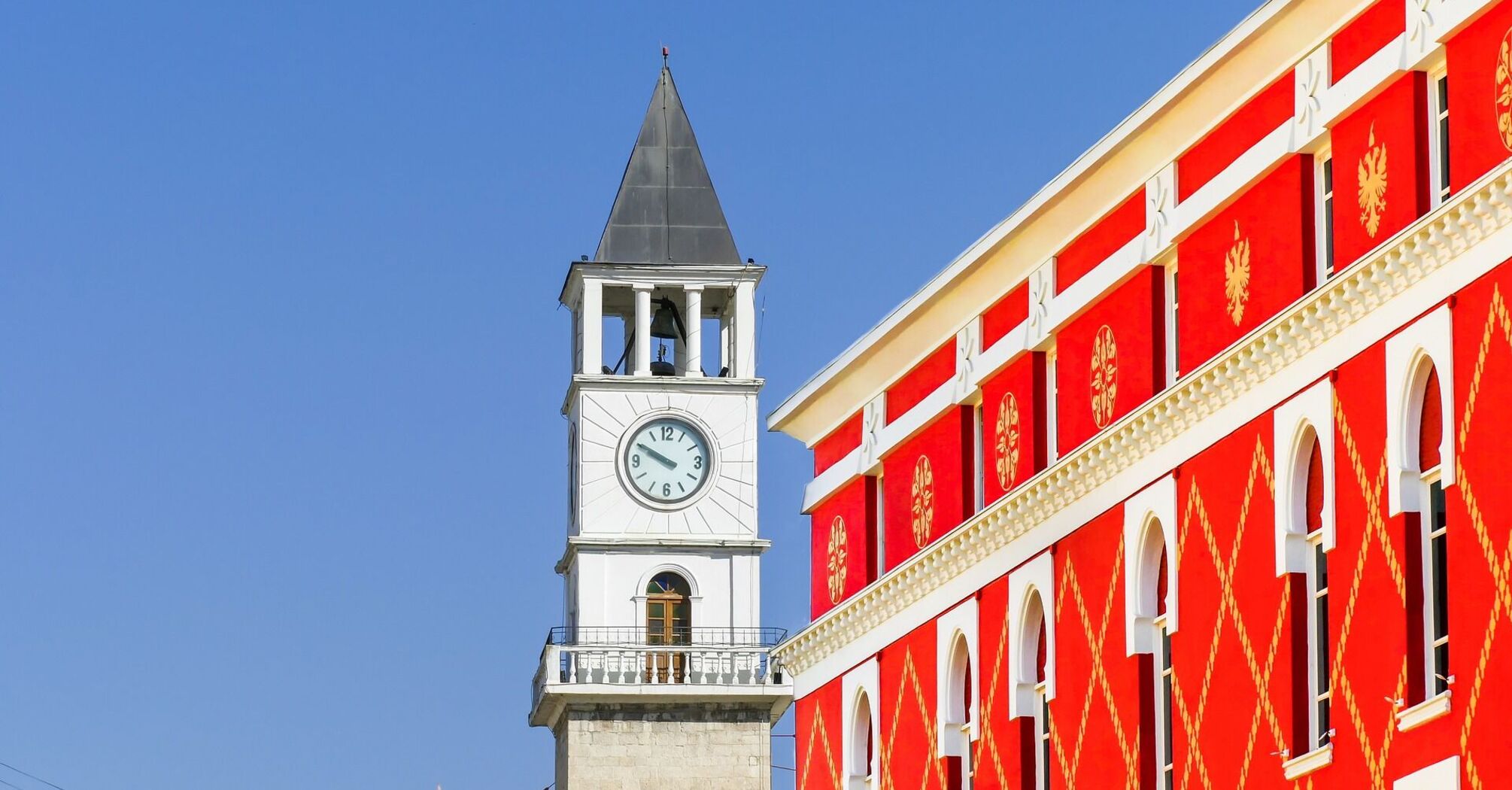 Clock tower of the historical building in Tirana, Albania against a clear blue sky