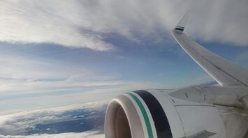 View from an Alaska Airlines plane window showing the wing and engine against a backdrop of clouds and sky